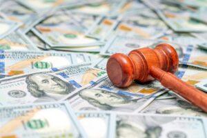 A gavel lying on a stack of money. Learn about the types of damages in personal injury cases in New York.