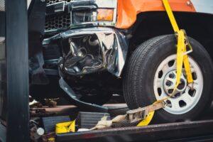 A damaged car on a truck, leading the owner to ponder the cost of hiring a truck accident lawyer in New York.