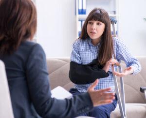 An injured office worker talks to a colleague about the possibility of suing her employer for a work injury in New York.