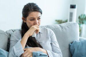 A grieving woman sits on a couch with a tissue and wonders, “Should my family get a lawyer for a potential wrongful death?”