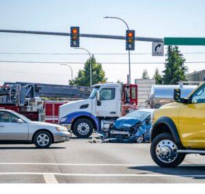 A damaged passenger car sits in an intersection after a crash involving a semi-truck. In New York, how the crash occurred and whether laws were violated can help determine liability.