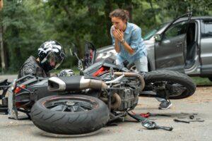 A motorcyclist lying next to his bike on the side of the road after an accident and wondering about their rights after this incident