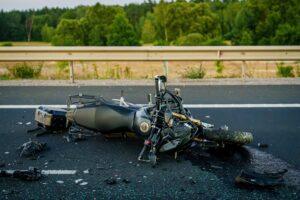 A motorcycle damaged in a crash, with someone nearby interested in learning about the top causes of motorcycle crashes in New York