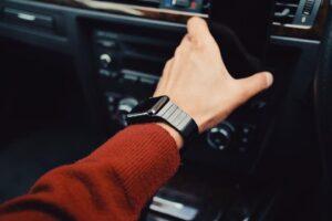A driver reaches for the dashboard of a car. Who is liable after an Uber or Lyft accident in New York?