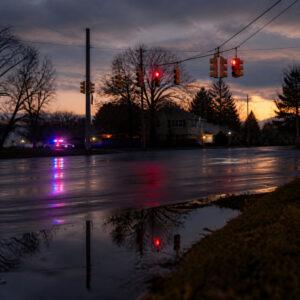 Long Island intersection at dusk with traffic signals and distant emergency lights